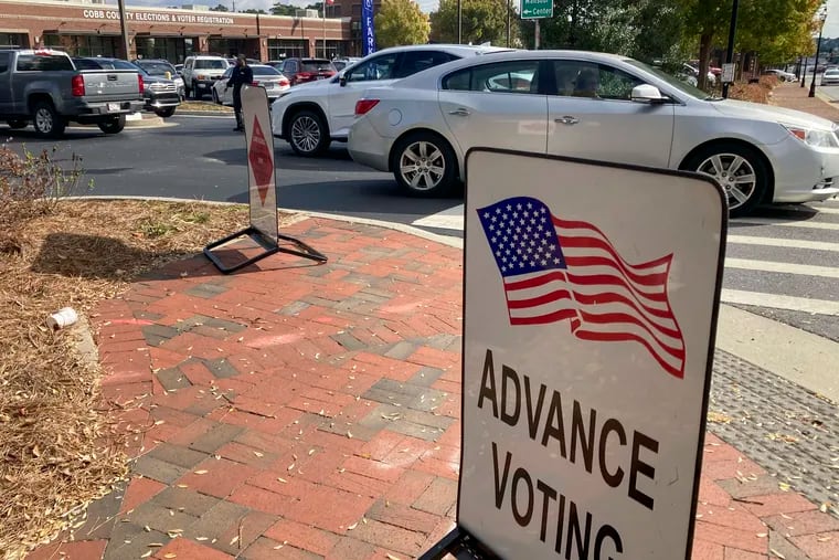 A sign showing the way for voters stands outside a Cobb County voting building during the first day of early voting, Monday, Oct. 17, 2022, in Marietta, Ga.