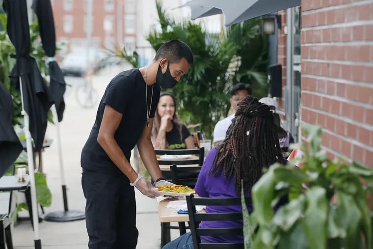 Tony Duk serves customers dining outside at his family's restaurant, Sophie's Kitchen, in South Philadephia in August. City Council has voted to extend expanded outdoor dining through next year.