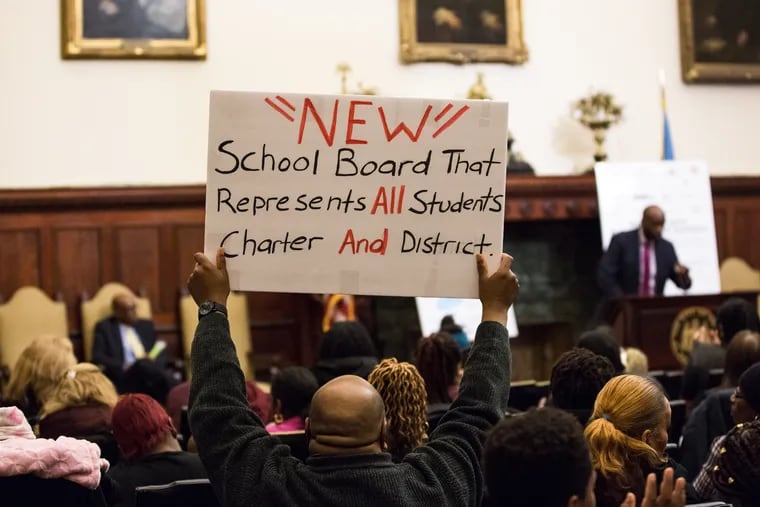 A charter school supporter holds up a sign during presentations given by city council members and charter advocates at City Hall in January. MICHELLE GUSTAFSON / For the Inquirer 