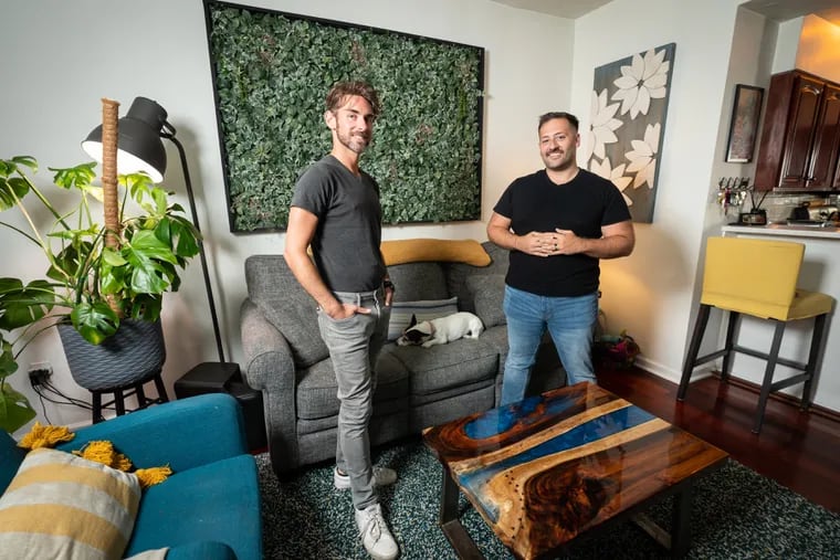 Frankie Rowles (left) and Chris Balbi with dog Maggie in the living room of their townhouse. The table is hand-crafted from a bench reclaimed from a church and adorned with resin.