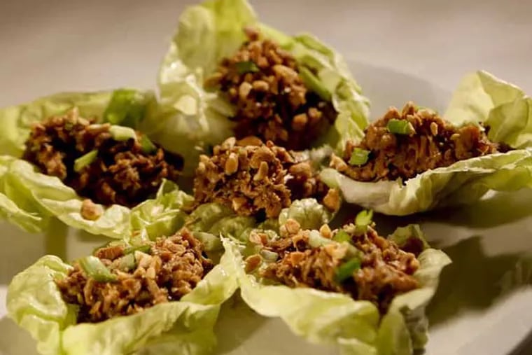 Cook rotisserie chicken with vegetables and spices, then serve in lettuce cups, with chopped roasted peanuts and green onion.