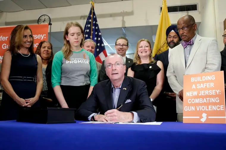 New Jersey Gov. Phil Murphy, center, signs a gun control bill during a ceremony in Berkeley Heights in 2019.