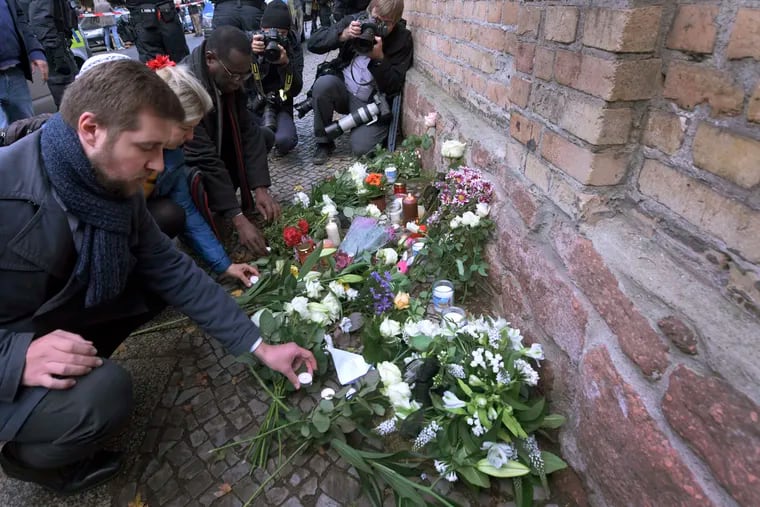 People place down flowers in front of a synagogue in Halle, Germany, Thursday, Oct. 10, 2019. A heavily armed assailant ranting about Jews tried to force his way into a synagogue in Germany on Yom Kippur, Judaism's holiest day, then shot two people to death nearby in an attack Wednesday that was livestreamed on a popular gaming site.