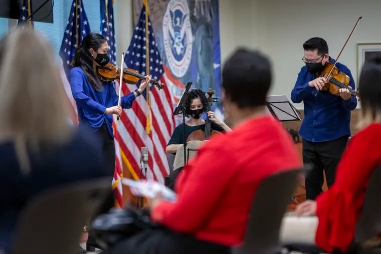 Philadelphia Orchestra members (from left) violinist Julia Li, cellist Yumi Kendall, and violist Che-Hung Chen perform for soon-to-be-naturalized U.S. citizens at the U.S. Citizenship and Immigration Services offices in Philadelphia on Thursday.