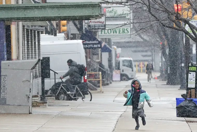 Tayani Scott, 6, runs down the street as snow falls outside of the Philadelphia Performing Arts Charter School in Philadelphia on Friday.
