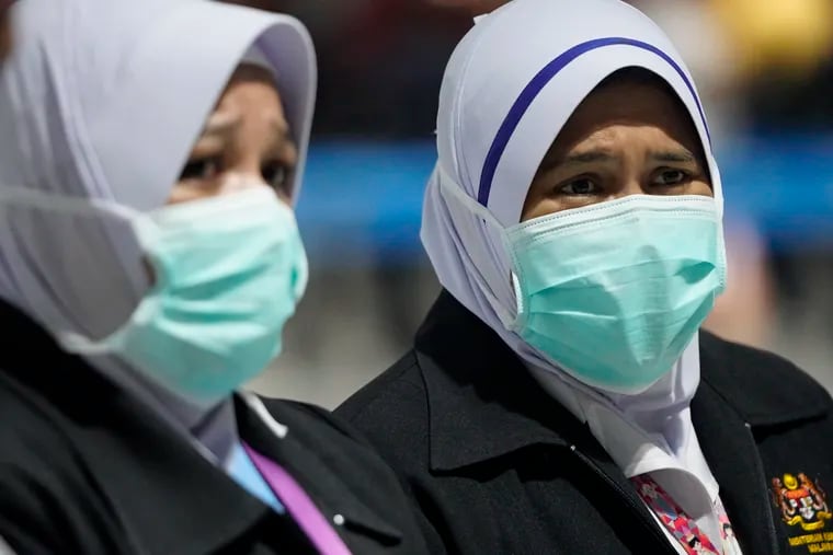 Health officials wear face masks at an inspection site at the Kuala Lumpur International Airport in Sepang, Malaysia, Tuesday, Jan. 21, 2020. Countries both in the Asia-Pacific and elsewhere have initiated body temperature checks at airports, railway stations, and along highways in hopes of catching those at risk of carrying a new coronavirus that has sickened more than 200 people in China.