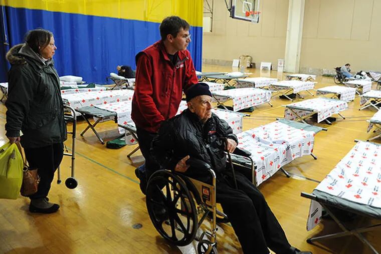 Bob Burns, 94, West Chester, is wheeled into the Red Cross shelter set-up at West Chester University by Red Cross spokesperson Dave Shrader Feb. 6, 2014.  At left accompanying Burns is his daughter Roberta Davis, 67, West Chester.   ( CLEM MURRAY / Staff Photographer )