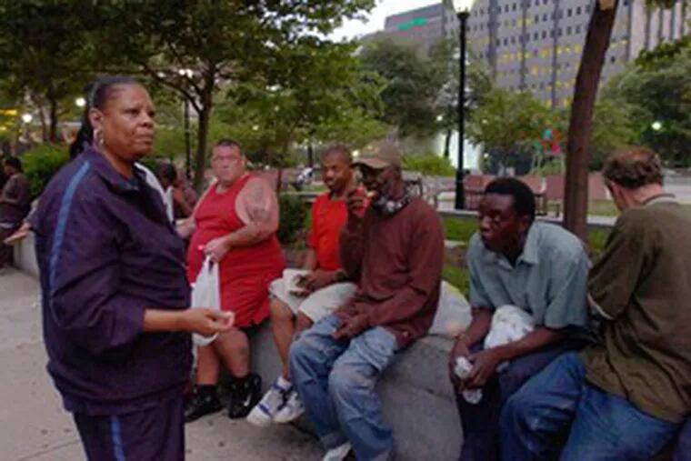 Veronica Joyner, chief executive officer of Mathematics, Civics and Sciences Charter School, talks with homeless men at JFK Plaza. She says she is determined not to halt the feeding program.