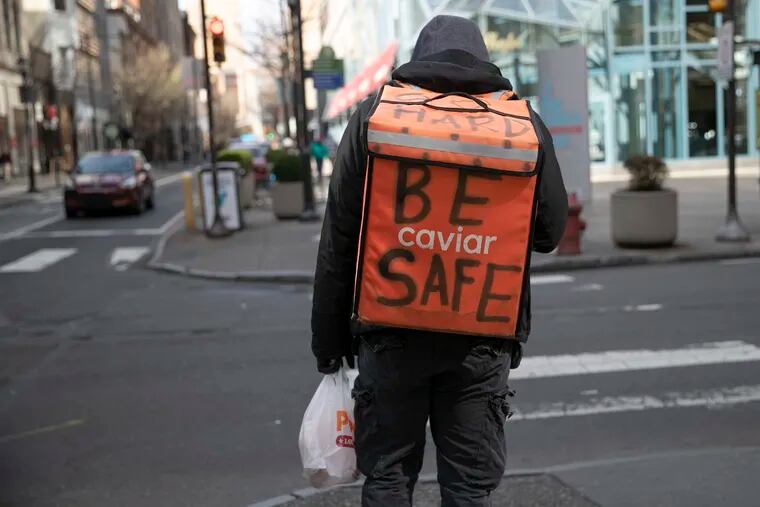 A food delivery worker with "Be Safe" written on his backpack while walking down Chestnut in Center City Philadelphia. The city's hospitality industry — lodging, food and drink service, travel and theme parks — was hit by government edicts aimed at reducing the spread of coronavirus.