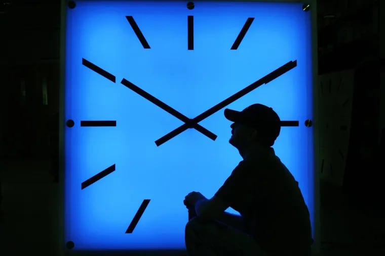 In this Oct. 30, 2008 file photo, Electric Time Company employee Dan Lamoore adjusts the color on a 67-inch square LED color-changing clock at the plant in Medfield, Mass.