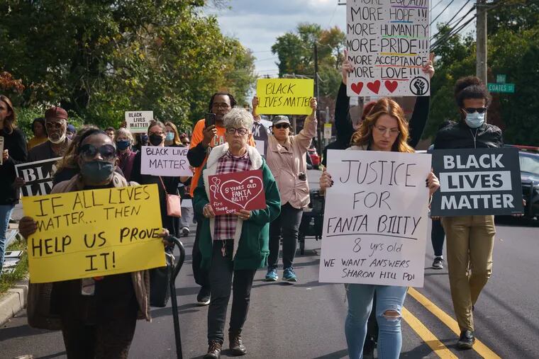 Protesters walk through Sharon Hill in the Justice for Fanta Bility silent march on Sunday.