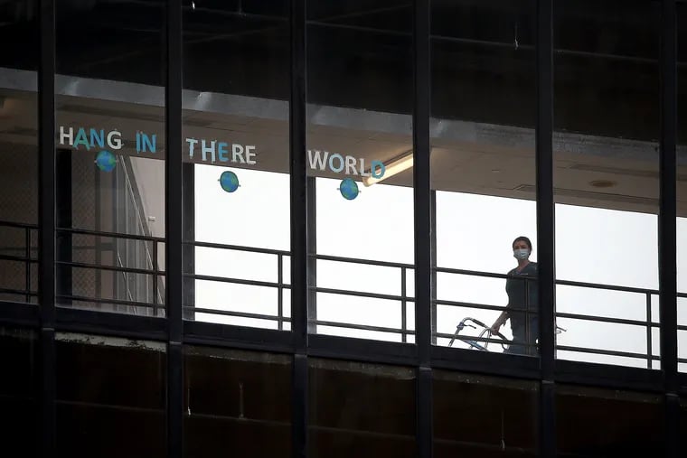 A sign that reads ”Hang in there world” is seen in the windows of the enclosed walkway at Thomas Jefferson University Hospital in Philadelphia Thursday.
