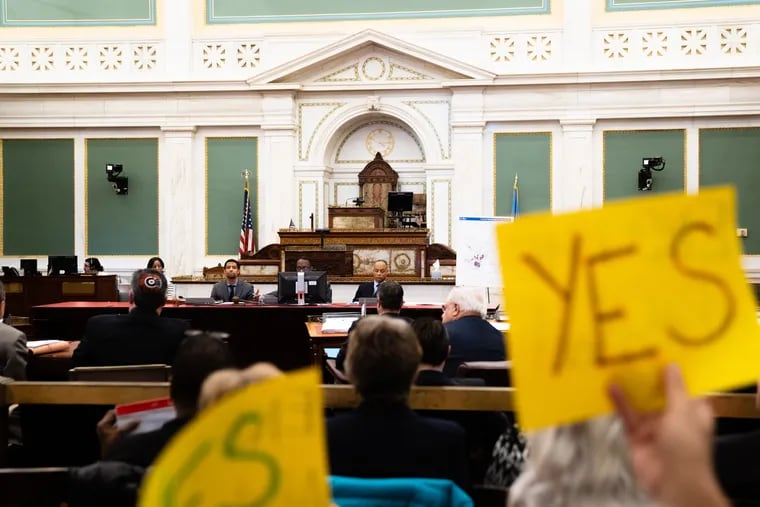 A Philadelphia resident holds a sign in support of a bill to change the 10-year tax abatement, during a Dec. 3 hearing on the legislation in City Hall.