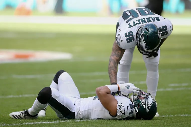 Eagles defensive end Derek Barnett, top, checking on linebacker Kamu Grugier-Hill after he was apparently injured early against the Miami Dolphins.
