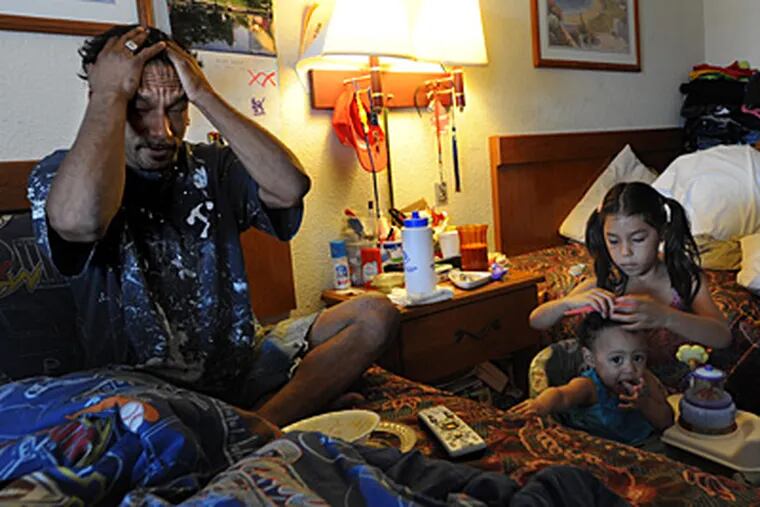 At the Hillside Inn in Cherry Hill, Robert Cordero rests on a bed as 8-year-old daughter Destiny grooms the hair of neighbor Kaylee Daniels, 9 months. With 2 other daughters and two sons, space is very tight. (April Saul/Staff)