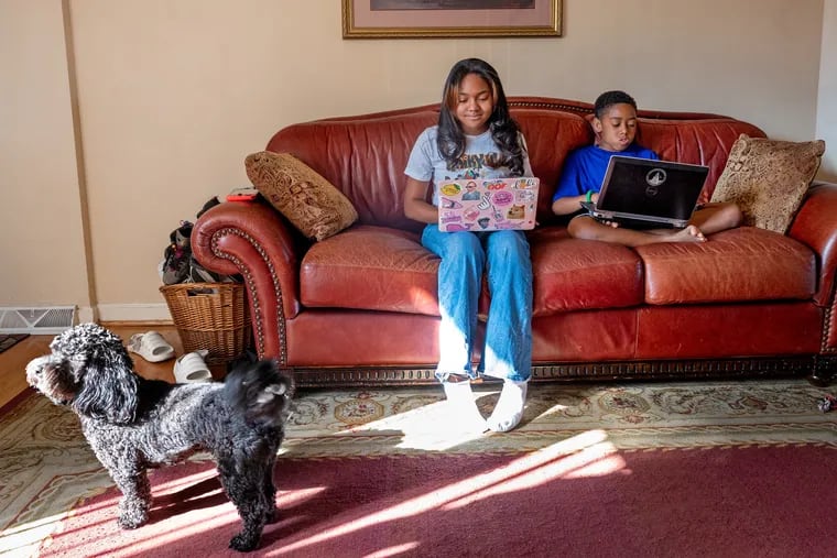 Milan Smalls (left), 16, and Nile Smalls (right), 9, with Zeke, their shih-poo at home. Both kids attend the virtual Buy the Hood summer camp, which teaches children as young as 5 the fundamentals of how money, investing, and budgeting work.