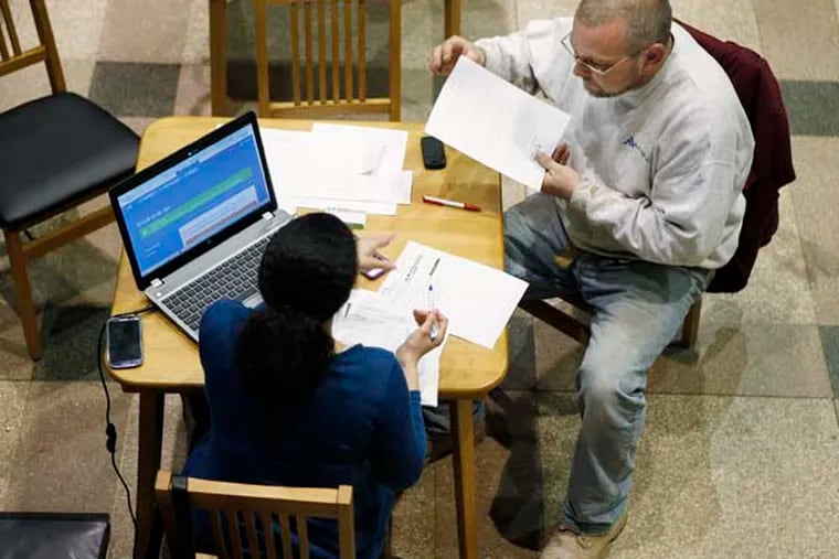 Tiffany Metts (left), a navigator with Resources for Human Development, helps John Brannigan, 48, apply for insurance through the Affordable Care Act. Brannigan, a self-employed construction worker said he got medical and dental insurance for under $200 a month. Resources for Human Development was at the Free Library of Philadelphia helping people apply online.   ( MICHAEL S. WIRTZ / Staff Photographer ) March 28, 2014.