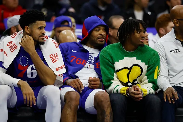 Sixers guard Tyrese Maxey (second from right) sits with assistant coach Sam Cassell and teammates P.J. Tucker (left) and Tobias Harris during the game against the Atlanta Hawks on Monday.