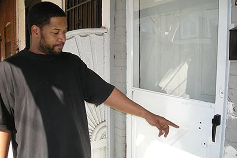 Clinton Rogers shows bullet holes in the front storm door of the East Germantown house where he lives.