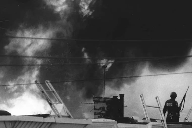 Police on an Osage Avenue roof as the fire rages out of control on May 13, 1985.