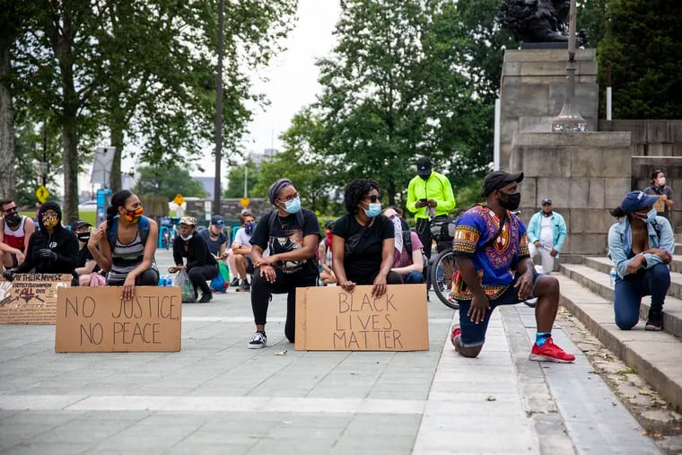 Protestor kneel at the steps of the Philadelphia Art Museum as they listen to speakers on Friday, June 5, 2020.