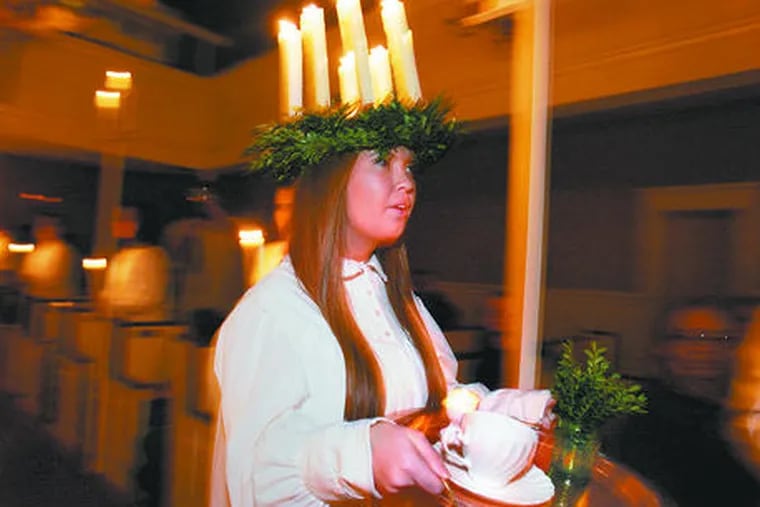 In a crown of burning candles, Emily Oakes as St. Lucy makes her way up the aisle during rehearsal at Gloria Dei (Old Swedes&#0039;) Church.