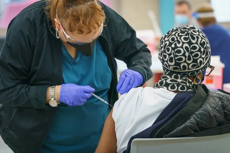 A member of the Health Department Clinic Staff, left, vaccinates a person at the Martin Luther King Jr. Older Adult Center in Philadelphia, Tuesday, February 23, 2021.