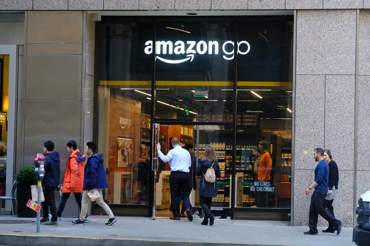 FILE - In this Jan. 30, 2019, file photo people walk past and into an Amazon Go store in San Francisco. Amazon, facing backlash from critics who say cashless stores discriminate against the poor, will soon accept cash at all its stores. The online shopping giant has more than 30 stores that don’t accept cash, including its book shops and Amazon Go convenience stores. (AP Photo/Eric Risberg, File)