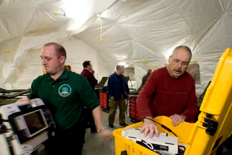 David Jackson (left), of Delaware County Memorial Hospital, and Jim Grace of the Huntingdon Fire Department unpack a case containing a cardiac monitor.