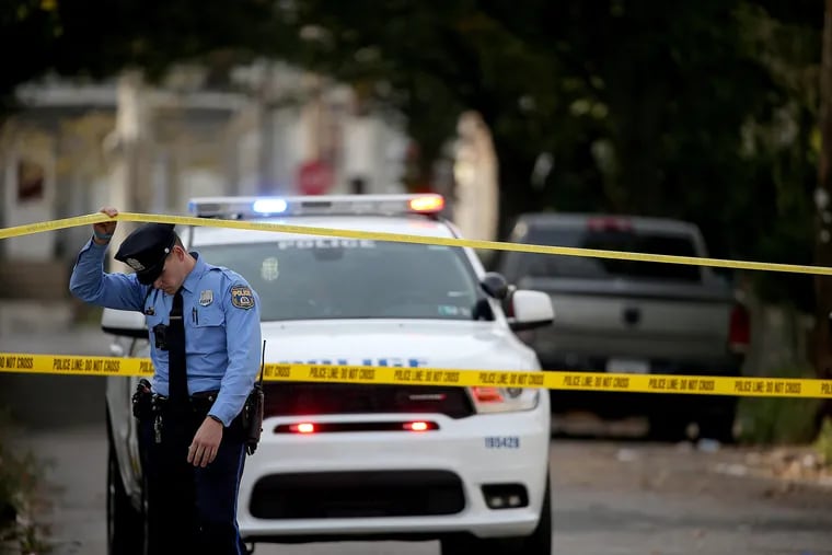 An unidentified Philadelphia police officer ducks under the tape as police gather at the scene on the 5700 block of Haddington Lane in Philadelphia, PA on November 11, 2019.