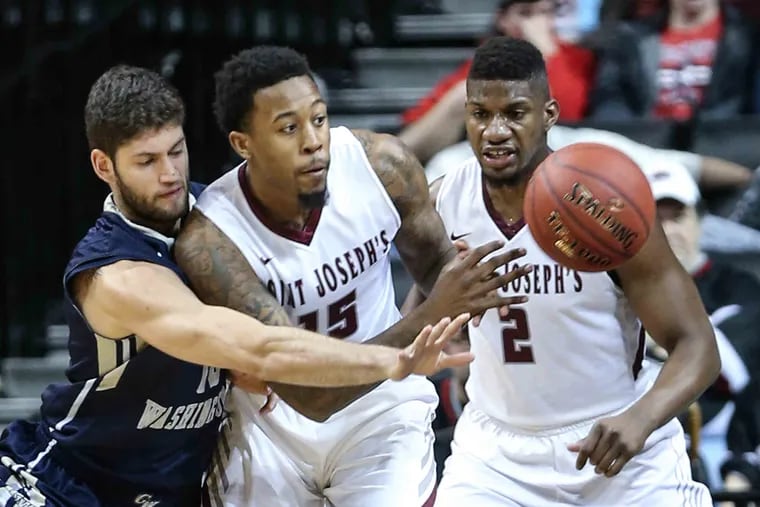 Isaiah Miles (center) tries to keep the ball away from a George Washington player.