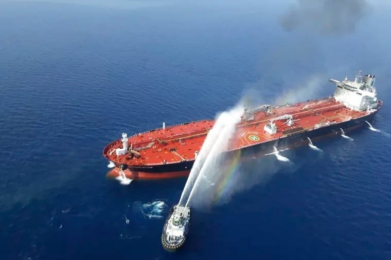 An Iranian navy boat sprays water to extinguish a fire on an oil tanker in the sea of Oman on Thursday. Two oil tankers near the strategic Strait of Hormuz came under a suspected attack Thursday.