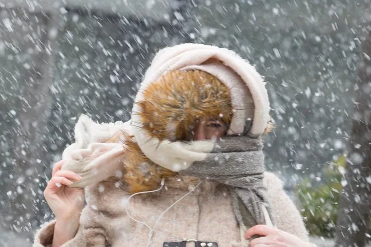 A pedestrian holds onto her scarf during Friday’s winter siege.