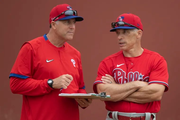 Phillies pitching coach Bryan Price (left) huddles with manager Joe Girardi during a spring-training practice in Clearwater, Fla.