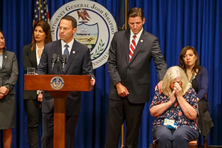 Daniel J. Dye (center), senior deputy attorney general, comforts Judy Deavena, mother of Joey Behe, a victim of sexual abuse from a Catholic priest, during Pennsylvania Attorney General Josh Shapiro's 2018 press conference on the findings of a grand jury report on clergy abuse.