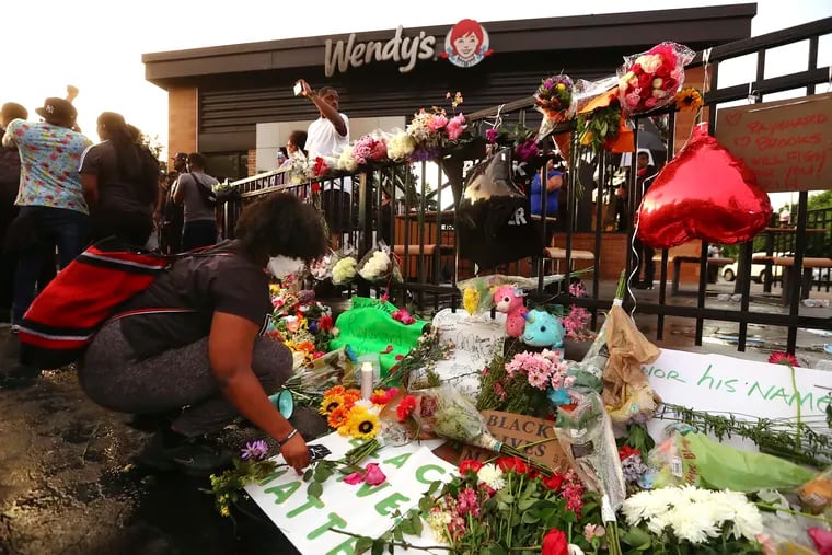 Tayla Myree sets out flowers on a shrine at a burned Wendy's on Sunday in Atlanta. Rayshard Brooks, a 27-year-old black man, was fatally shot by a white Atlanta police officer outside the Wendy's on Friday night.