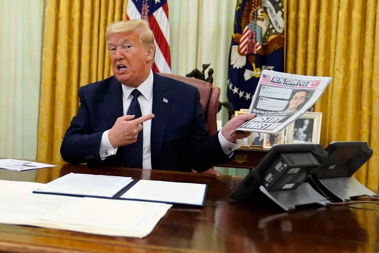 President Donald Trump holds up a copy of the New York Post as speaks before signing an executive order aimed at curbing protections for social media giants.