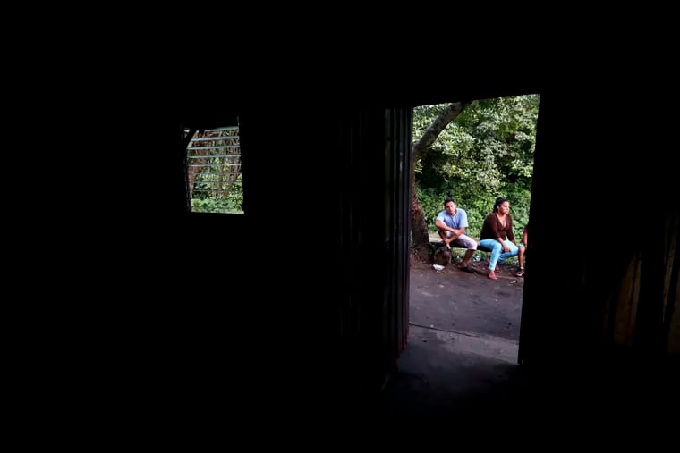In this Oct. 12, 2019 photo, members of a family sit outside their makeshift house, after being threatened by gangs in Oratorio de Concepcion, El Salvador. The family had to leave their home, carrying only what they were wearing and taking refuge in this place.