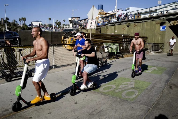 In this July 1, 2018 photo people ride Lime and Bird scooters along the strand in Santa Monica, Calif.