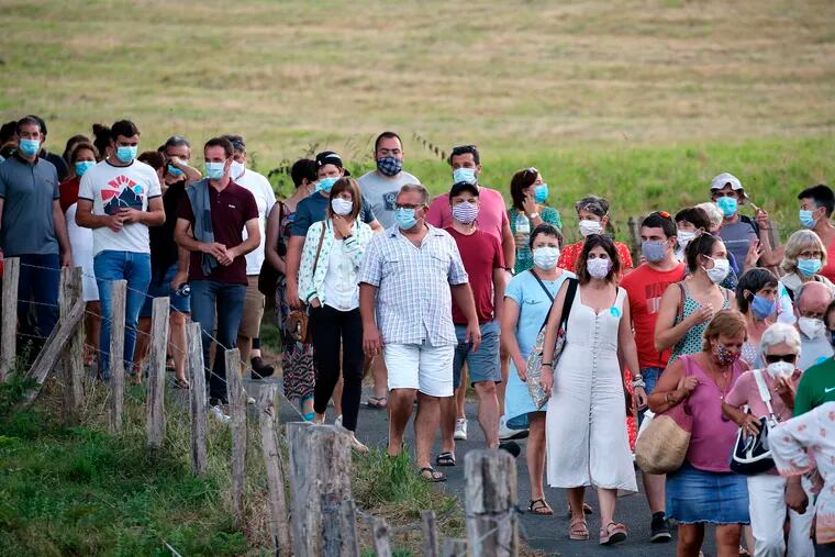 People wear face masks as they leave a music festival in Saint Etienne de Baigorry, southwestern France, on July 26, 2020.