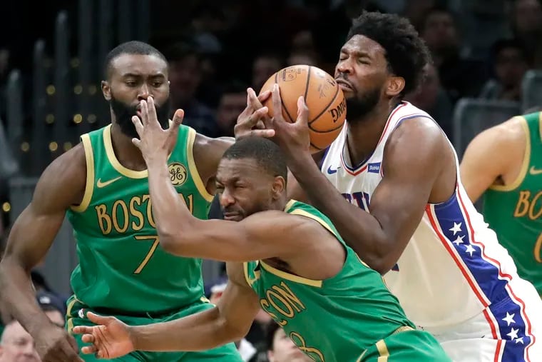 Joel Embiid controls the ball against Celtics guards Kemba Walker (8) and Jaylen Brown (7) in the second half.