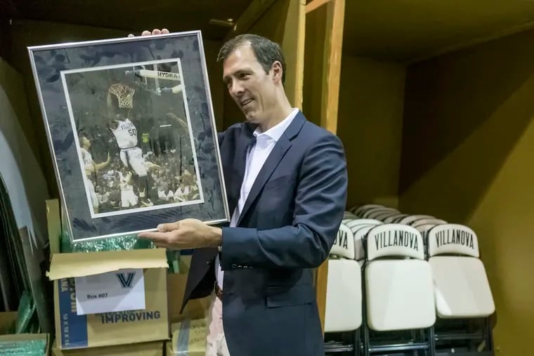Scott Reidenbach, at his King of Prussia warehouse, looks over a photograph of Will Sheridan dunking against Temple.