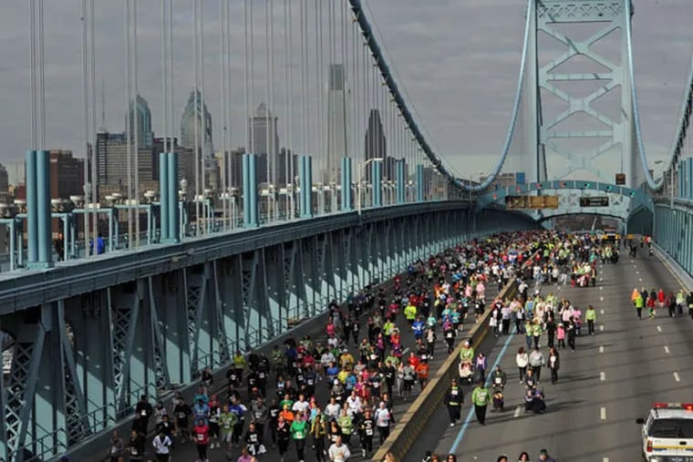 Runners and walkers cross the Ben Franklin Bridge during a benefit event. Officials say that up to 100,000 pedestrians will cross the bridge each day of Pope Francis’ visit — and that each will be screened. (APRIL SAUL / File Photograph)