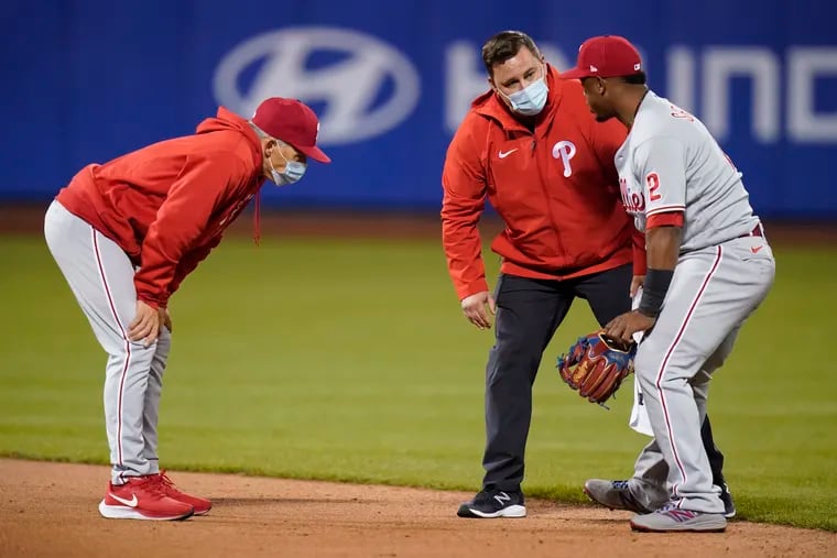 Phillies manager Joe Girardi, left, watches as a trainer checks on shortstop Jean Segura during the sixth inning of Wednesday night's 5-1 loss to the Mets in New York.