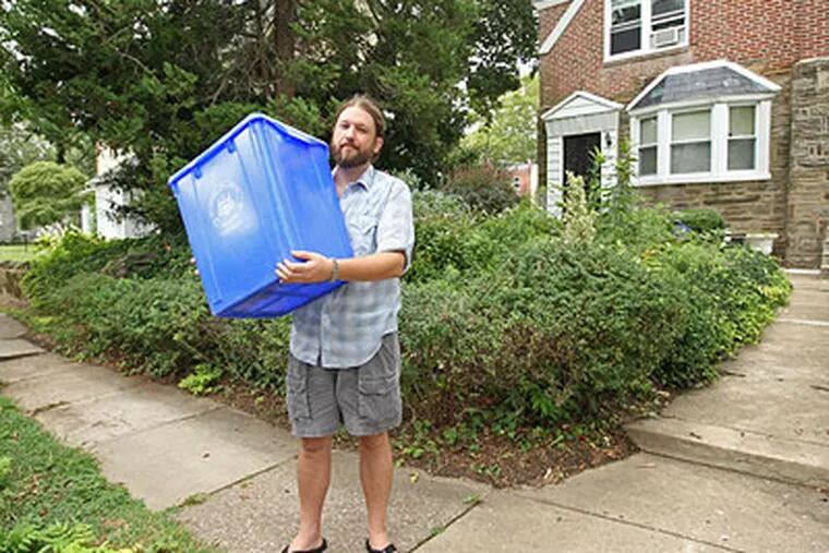 Kevin Stutler holds up the Blue City Recycle bin he left out on the curb the day he ws cited for not recycling. (Michael Bryant / Staff Photographer)
