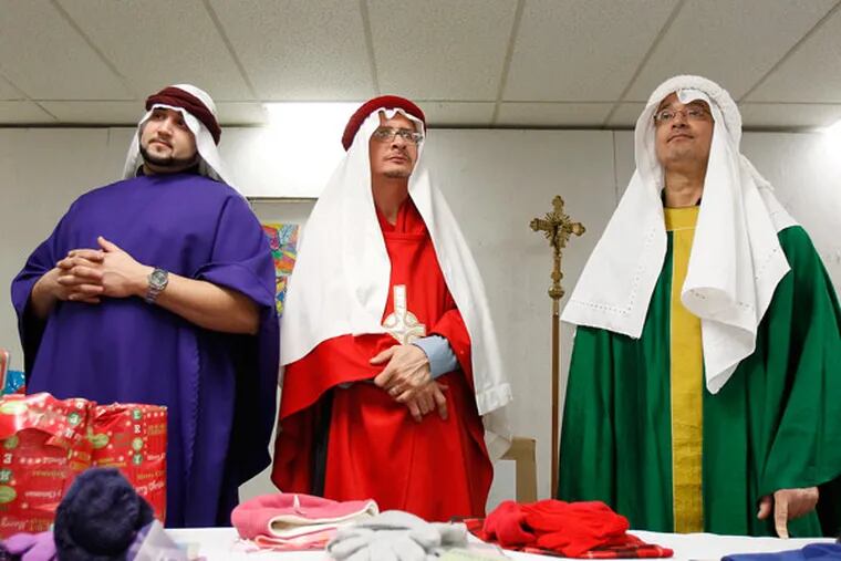 Jose Figueroa Jr. (from left), Francisco Torres, and Jose Figueroa Sr. wait to give out toys at the Feast of the Three Kings at St. Anthony of Padua parish in Camden. (David Maialetti / Staff Photographer)