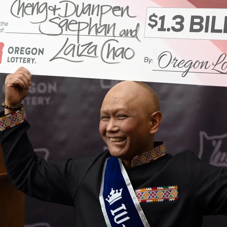 Cheng "Charlie" Saephan holds a check above his head after speaking during a news conference where it was revealed that he was one of the winners of the $1.3 billion Powerball jackpot at the Oregon Lottery headquarters on Monday, April 29, 2024, in Salem, Ore.