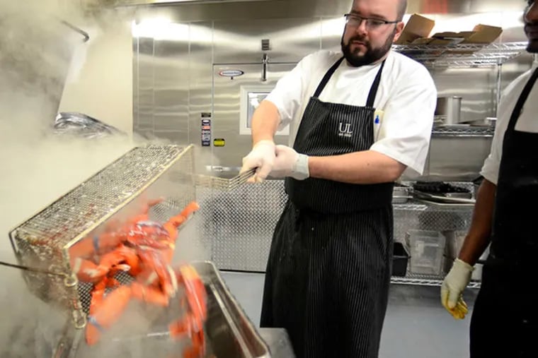 Banquet chef Matthew DiGiovanni (left) and Hailu Godoy work with lobsters in preparation for the Union League's champagne-filled New Year's Eve party.