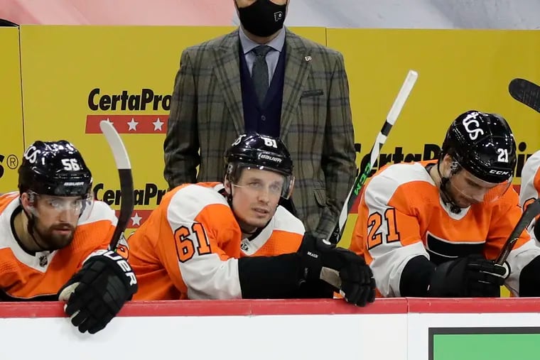 Flyers coach Alain Vigneault watches his team play the Boston Bruins with Flyers defensemen Erik Gustafsson, Justin Braun and center Scott Laughton on the bench on Feb. 5.