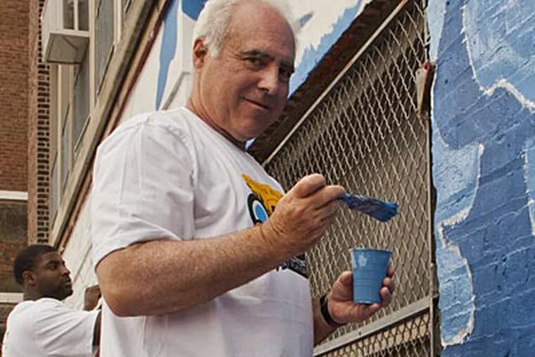 Eagles owner Jeffrey Lurie helps paint a mural at Comegys Elementary School on Wednesday. (Elise Wrabetz/Staff Photographer)